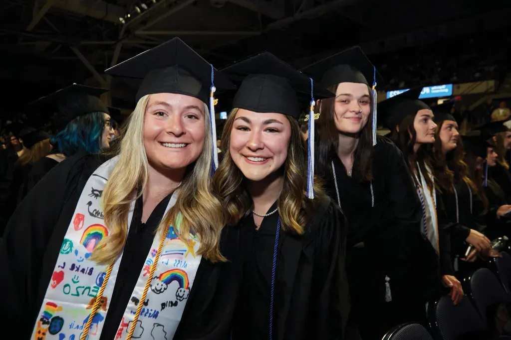 two students smile for the camera at commencement