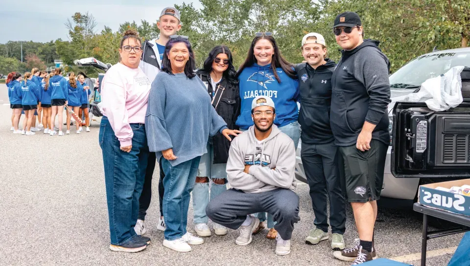 A family poses together at a U N E football tailgate