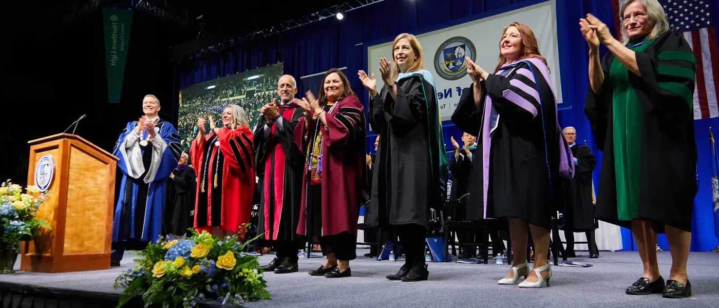 President James D. Herbert and the deans of the University of New England clap on the stage in congratulations to all the 2024 UNE graduates. 